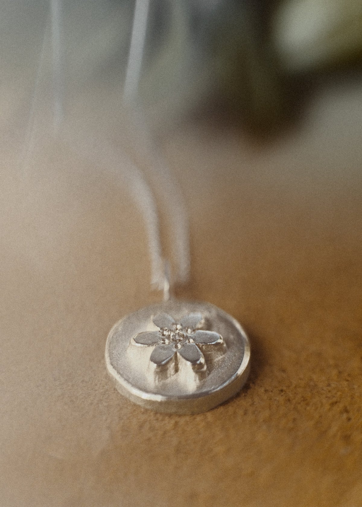 close up small disc floral pendant with diamond at its centre