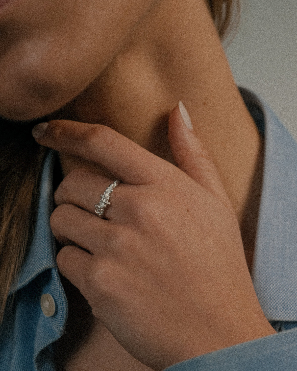 Close-up of a hand wearing a seaweed ring with a blue denim jacket