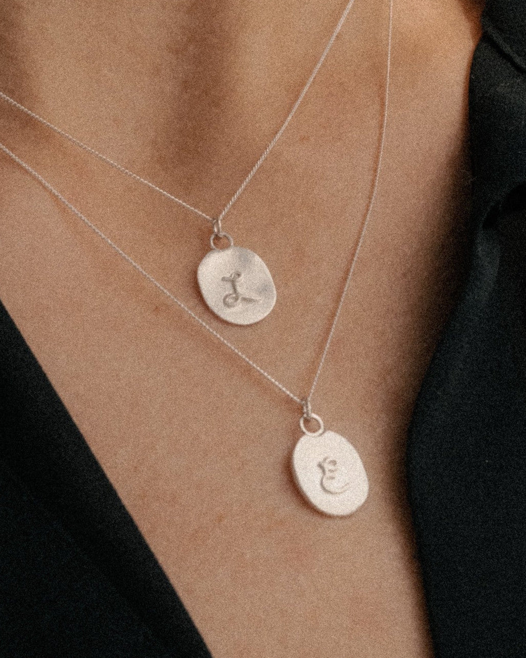 Layer silver initial pendants on a model