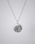 Silver necklace with a round pendant and olive branch engraving on a light gray background