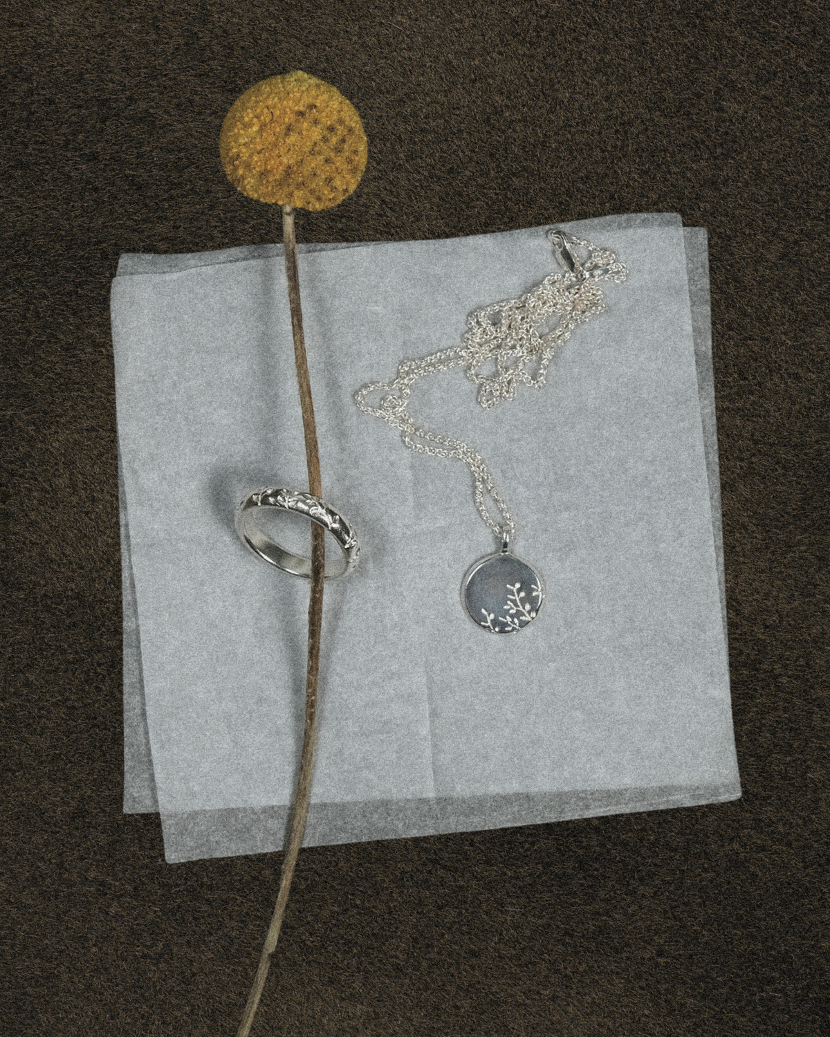 olive engraved ring and pendant with a yellow flower on dark green abckground