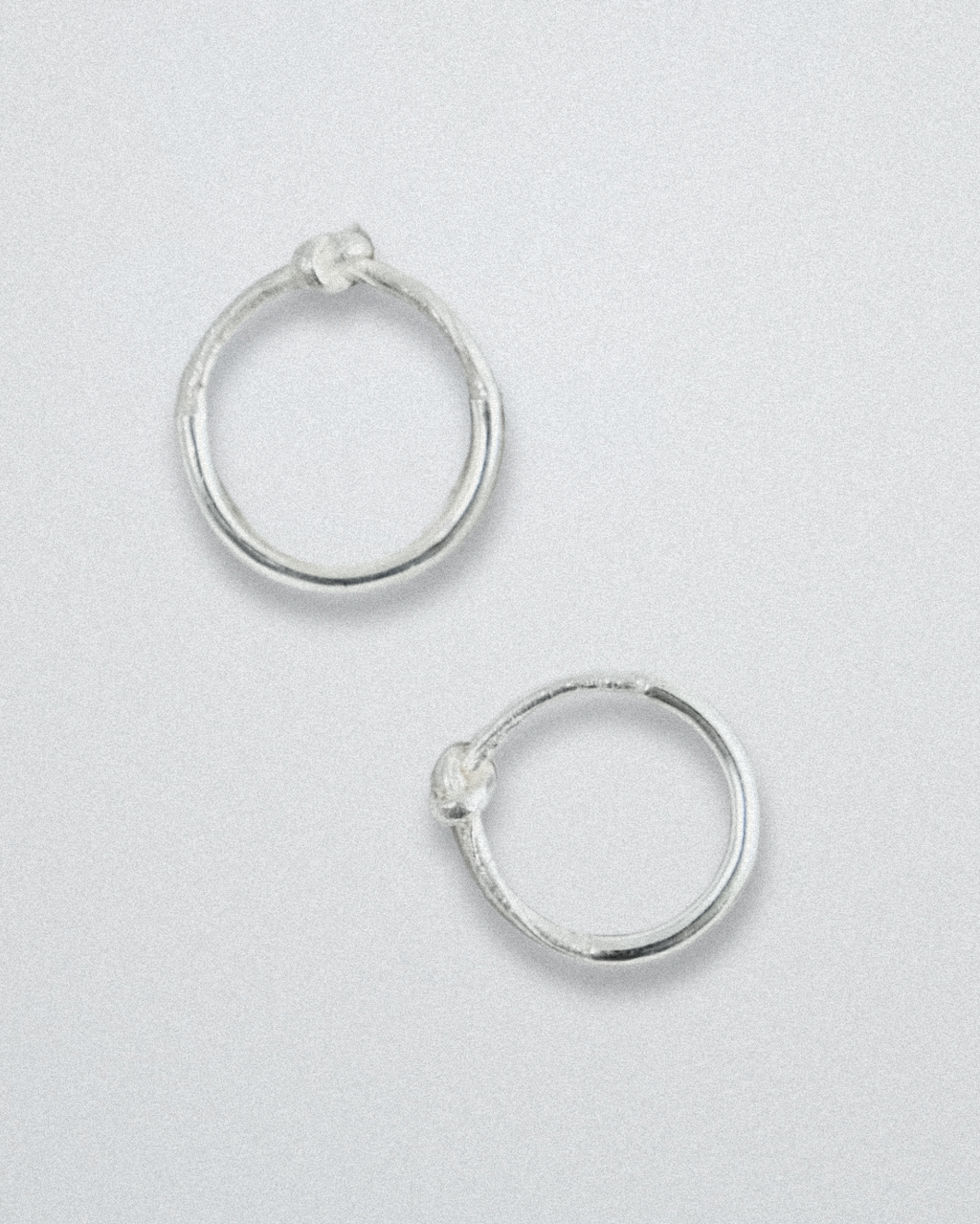 Pair of silver knot rings on a light gray background