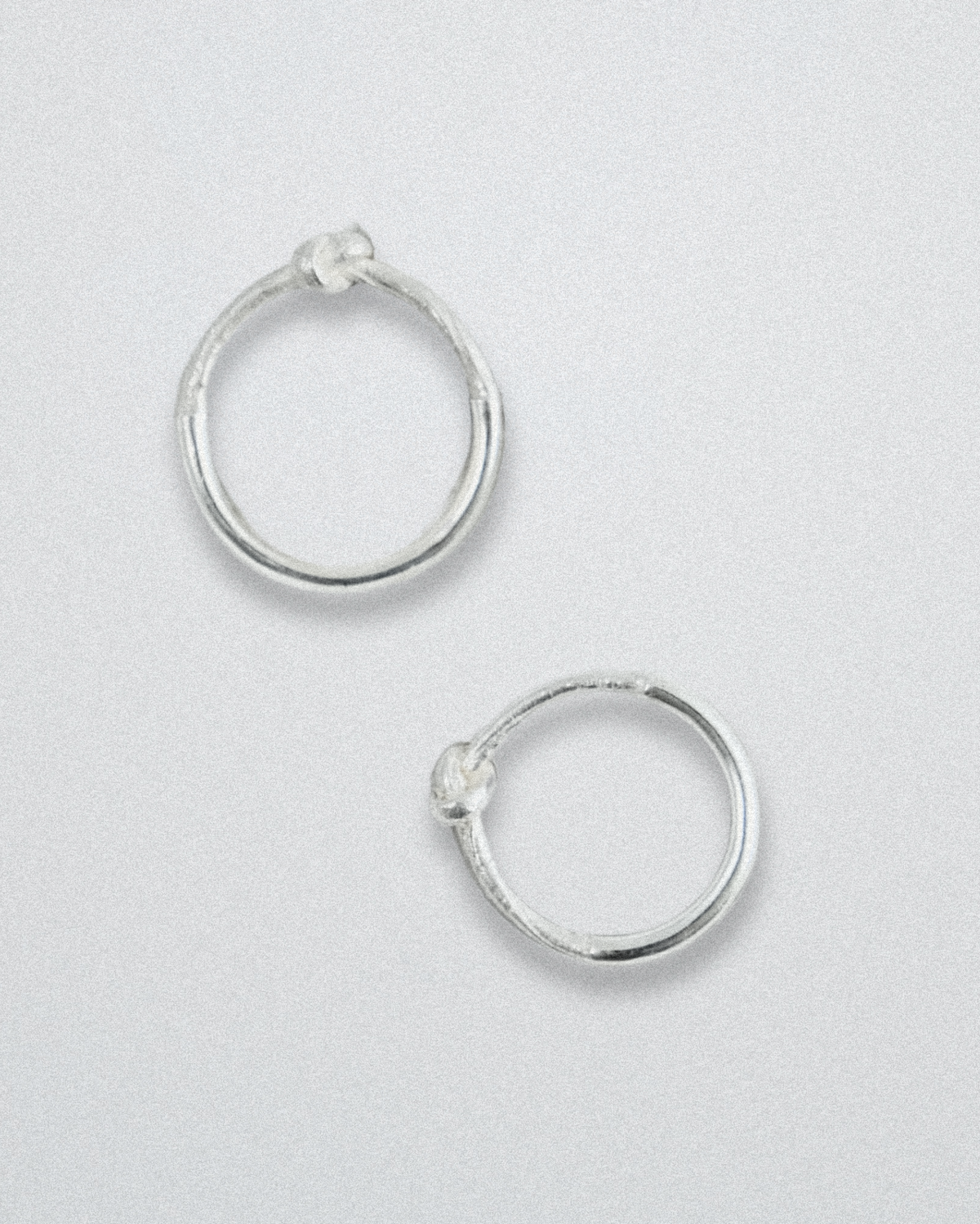 Pair of silver knot rings on a light gray background