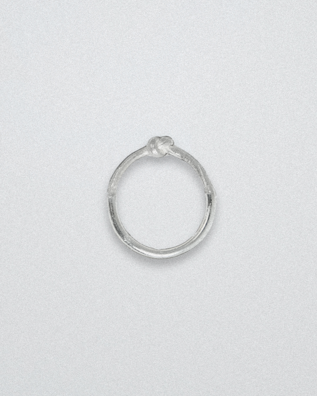 Silver ring with knot detail on a light gray background