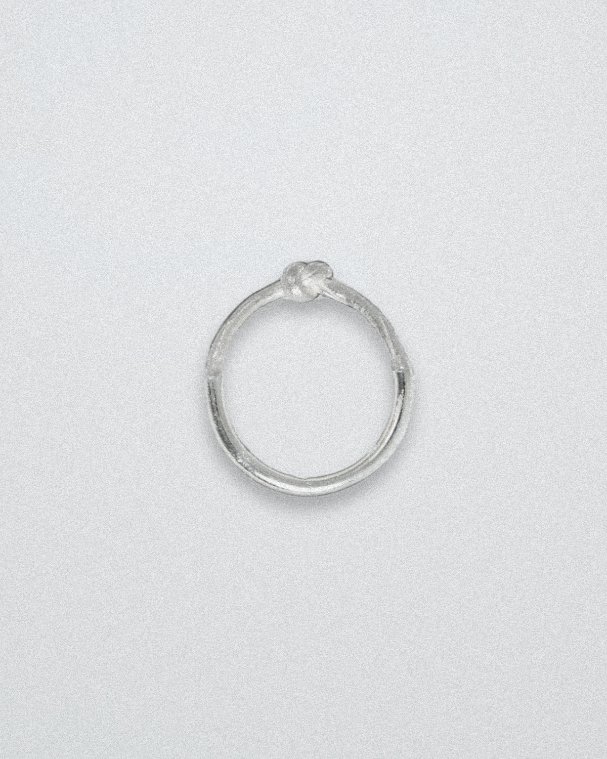 Silver ring with knot detail on a light gray background