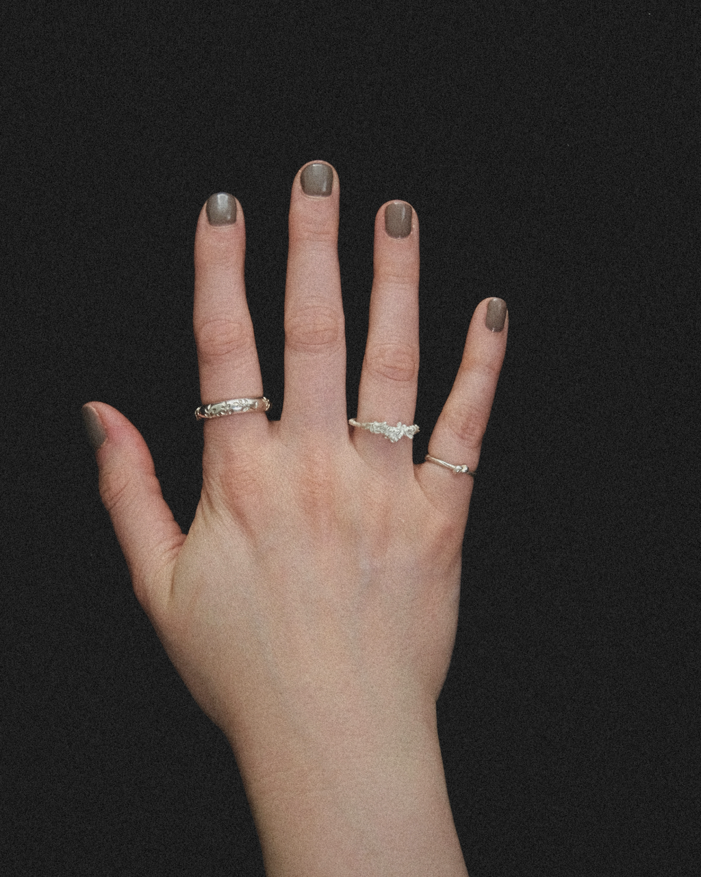 Hand with wedding, seaweed and knot rings from THEA STUDIO on a black background